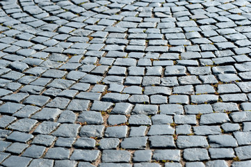 Pavement stone blocks of dark stone of the old part of the city. Textured background