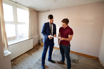 Obraz na płótnie Canvas Male First Time Buyer Looking At House Survey With Realtor