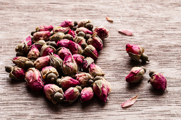 Pink red dried rose buds heart shaped on old wooden table with copyspace.