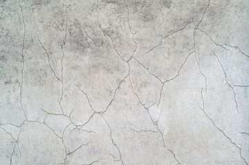 White concrete wall of the old house with curly cracks and swollen white paint. Background