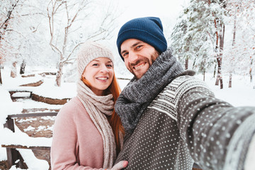 Young couple taking a selfie in a park on a snowy day