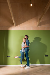 loving family couple hugging by green wall in apartment