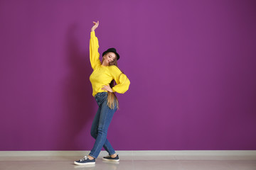 Beautiful young woman dancing near color wall