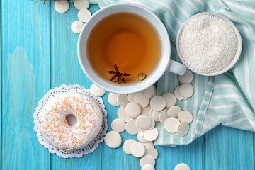 Sweet donut, chips and cup of tea on color wooden table