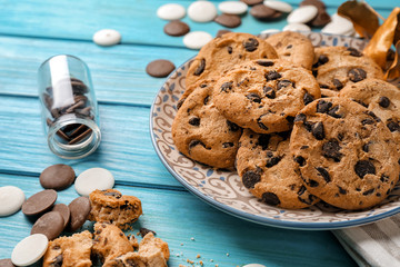 Plate with tasty chocolate chip cookies on color wooden table