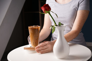 Woman with glass cup of tasty frappe coffee at table