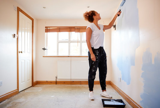 Woman Decorating Room In New Home Painting Wall