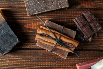 Soap bars with cinnamon sticks and chocolate on wooden table