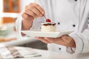 Male chef with tasty dessert in kitchen, closeup
