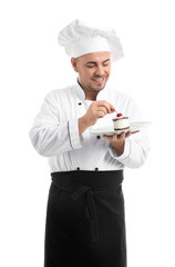 Male chef with tasty dessert on white background
