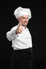 Naklejka premium Portrait of male chef showing thumb-up on dark background