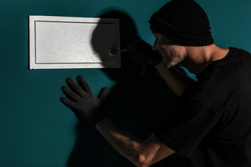 Male thief breaking safe indoors