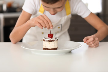 Obraz na płótnie Canvas Cute little chef with tasty dessert in kitchen