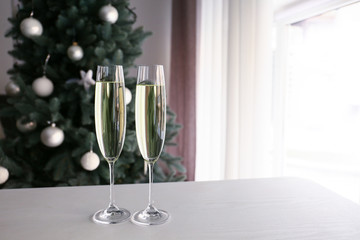 Glasses of champagne on table in room decorated for Christmas