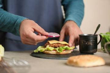 Obraz na płótnie Canvas Male chef preparing burger in kitchen