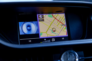 Modern built-in navigator in the car in the panel with the image of the map on the display and voice control paves the route without buttons close-ups.