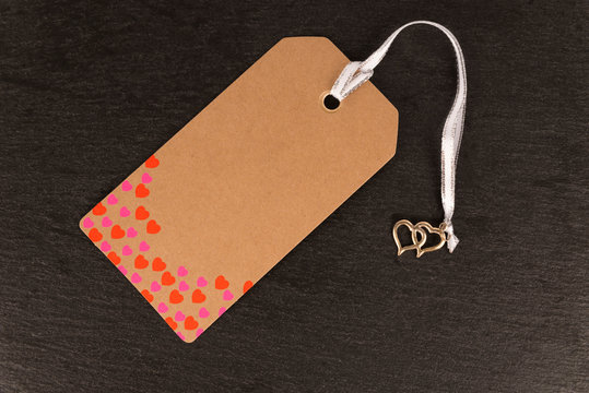 Blank old paper cloth tag or label isolated on a dark slate background. Heart shape pattern.