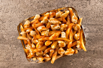 Poutine in a takeout container. Cooked with french fries, beef gravy and curd cheese. Canadian cuisine. - 239359400