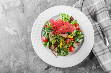 Fresh green salad with lettuce, arugula, sweet pepper, tomatoes and beef in plate over dark table. Healthy food, dieting, top view, copy space