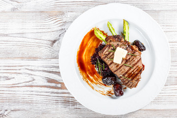 Grilled pork chop steak with dates in honey, rosemary, asparagus and beet salad on wooden background. Hot Meat Dishes. Top view, flat lay
