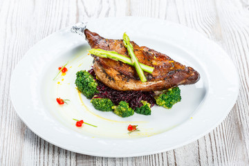 Grilled pork chop steak on the bone with asparagus and broccoli on light wooden background close up. Hot Meat Dishes. Top view