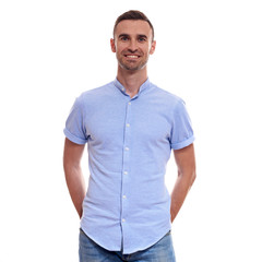 Fototapeta premium Casually handsome. Confident young handsome man in jeans shirt keeping arms crossed and smiling while standing against white background