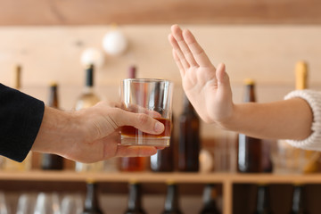 Man with glass of whiskey and woman refusing to drink in bar