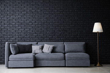 Stylish interior of room with comfortable big sofa near dark brick wall - Powered by Adobe