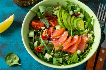 Diet menu, Vegan food close-up. Healthy salad with quinoa, arugula, Tomatoes, Salmon and Avocado on blue concrete or stone table.