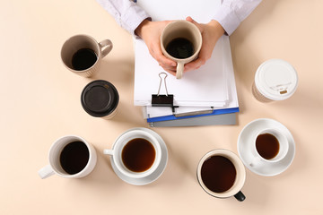 Businesswoman with a lot of empty cups of coffee sitting at table. Concept of addiction