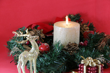 Two glasses of champagne, a golden candle, a wreath on a red background