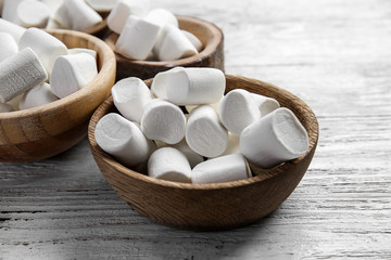 Bowls with tasty marshmallow on wooden background