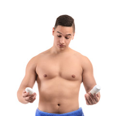 Young man with different types of deodorant on white background