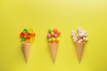 Composition with tasty sweets and waffle cones on color background