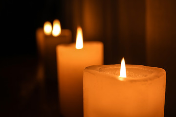 Burning candles in darkness, closeup