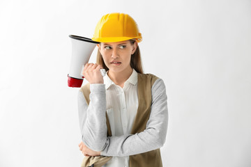 Thoughtful female engineer with megaphone on white background