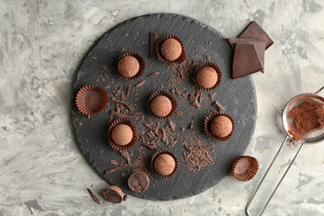 Slate plate with sweet truffles on grey table