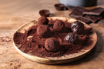 Tasty sweet truffles on wooden plate