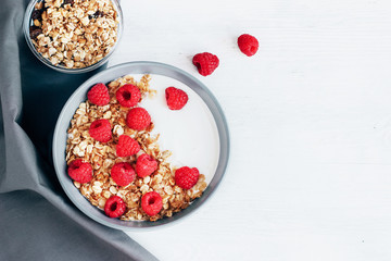 Fototapeta na wymiar Healthy Breakfast yogurt with granola and raspberry on white wooden background top view