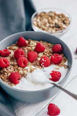 Healthy Breakfast yogurt with granola and raspberry on white wooden background top view