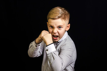 Angry boy with a black eye is threatening his fist. Bully 9-year-old with a shiner. White background, front view.