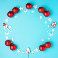 Christmas composition. Wreath made of snowflakes, red balls and lollipops on pastel blue background. Christmas, winter, new year concept. Flat lay, top view, copy space