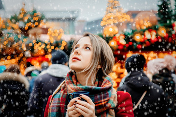 Beautiful adult girl with cup of hot drink at Christmas fair in Dresden, Germany