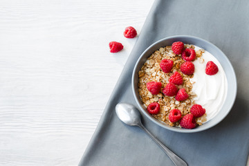 Healthy Breakfast yogurt with granola and raspberry on white wooden background top view copy space