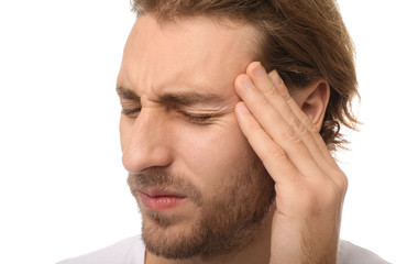 Young man suffering from headache on white background, closeup