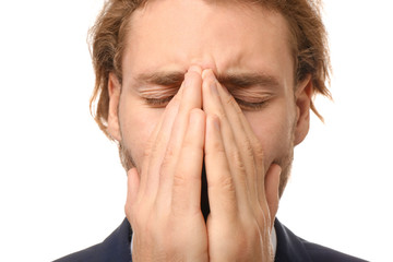 Young businessman suffering from headache on white background, closeup