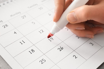 Female hand encircling date in calendar, closeup