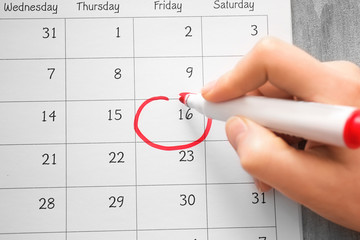 Female hand encircling date in calendar, closeup
