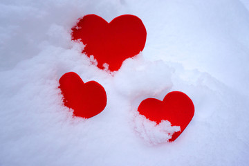Three red hearts in snow. Love concept. Valentines celebration. Romance symbol.      