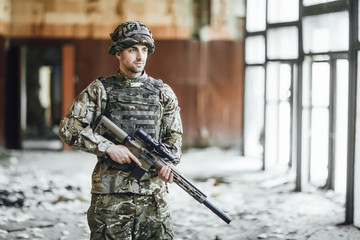 Patrols the territory! The young soldier in the military stands at the window of the collapsed...